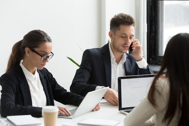 Executive business people using laptops for work, talking on phone