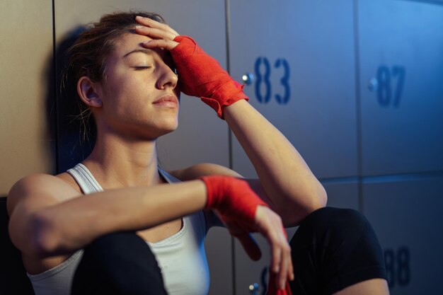 Free photo exhausted athletic woman resting with eyes closed in a locker room after the workoutxa