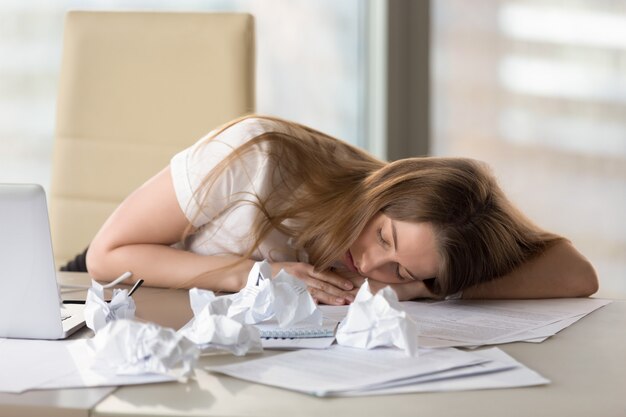 Exhausted tired woman sleeping at desk after overwork in office