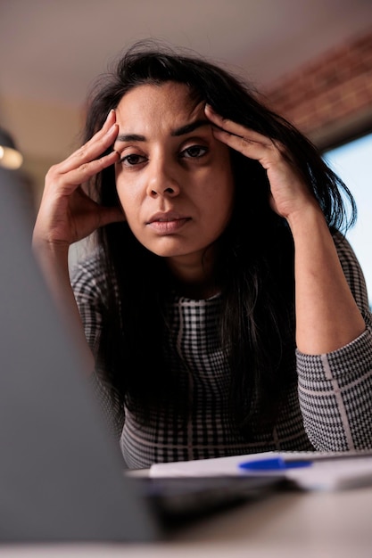 Exhausted worker feeling frustrated about deadline, working from home on laptop. Being tired and sleepy, stressed about business job and feeling overworked with headache. Burnout pain.