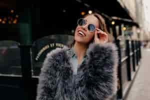 Free photo exited stylish lady in trendy outfit in the city. fashion portrait pretty woman in fur coat