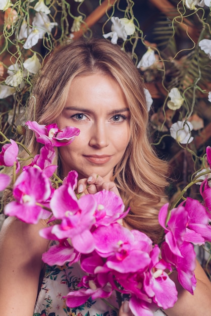 Free photo exotic fresh orchid flowers in front of blonde young woman