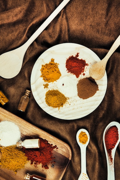 Free photo exotic spices with plate and spoons on cloth