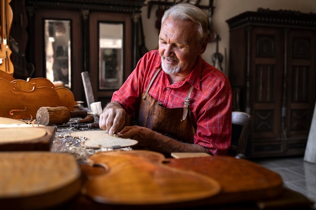 An experienced gray haired senior carpenter working on his project in carpentry workshop