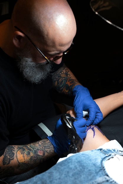 Free photo experienced tattoo artist working on client tattoo