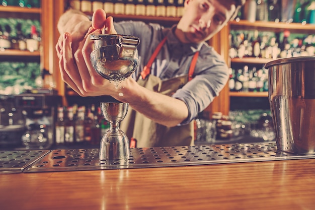 Free photo expert barman is making cocktail at night club.