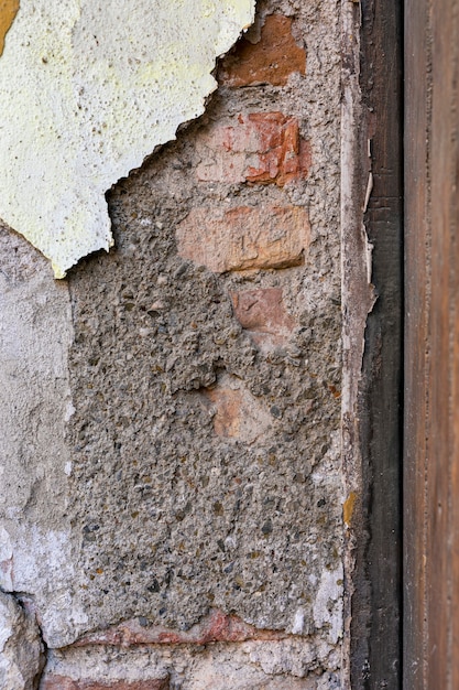 Exposed brick wall with peeling concrete surface