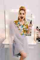 Free photo expressing true positive emotions of fashionable pretty model in tulle skirt, with luxury coiffure, makeup, glass of champagne in hairdresser salon