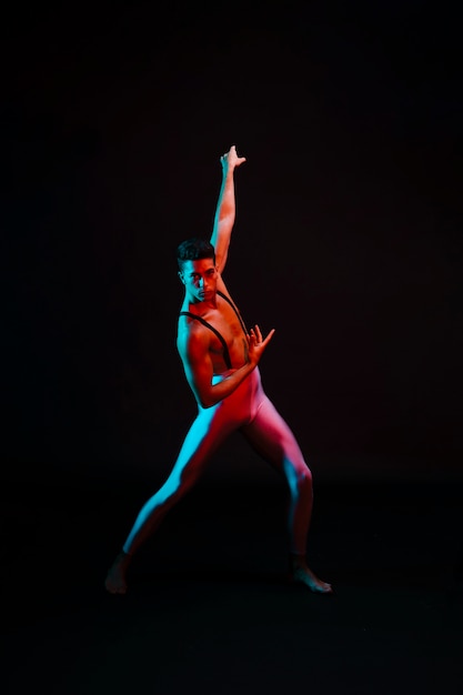 Expressive male ballet dancer in leotard standing in spotlight