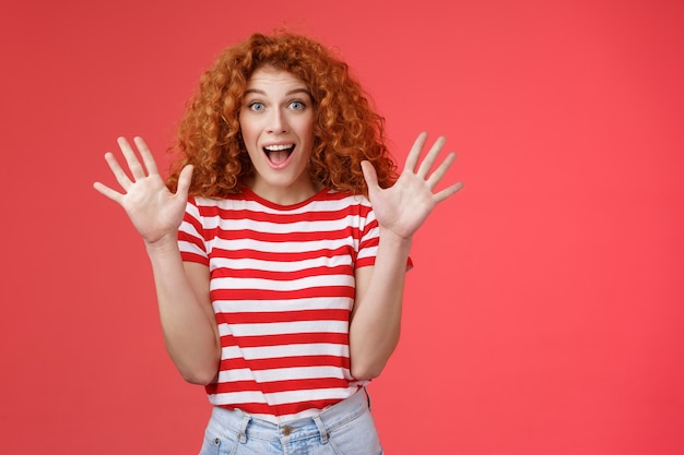 Free photo extremely wonderful news she excited. thrilled emotive gorgeous redhead woman scream amazed awesome surprise raise hands waving impressed open mouth stare charmed fascinated red background.