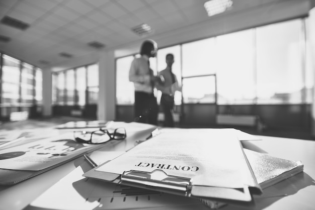 Eyeglasses on a office desk fulll papers in black and white