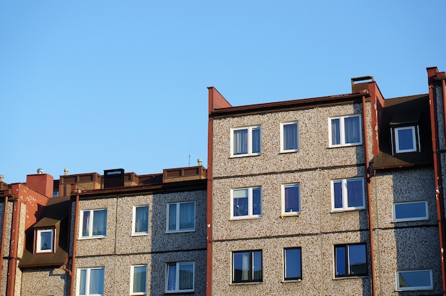 Free photo facade of a row of apartment buildings against a clear blue sky