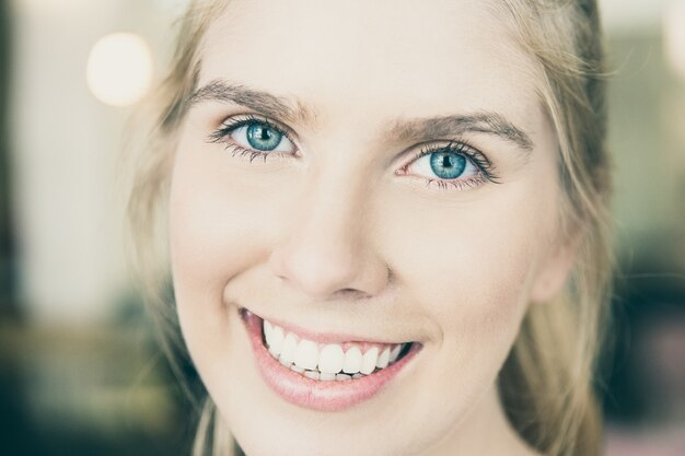 Face of happy beautiful young blonde woman with blue eyes and white teeth