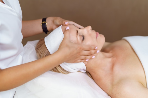 Face massage. Close-up of adult woman getting spa massage treatment at beauty spa salon. Spa skin and body care. Facial beauty treatment. Cosmetology.