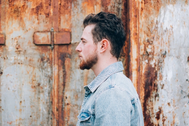 Face profile of a handsome young Caucasian man wearing a jean jacket posing outdoors