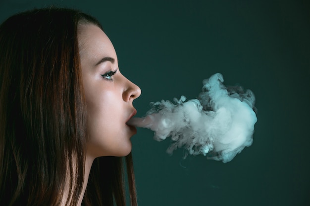 Free photo the face of vaping young woman at black studio