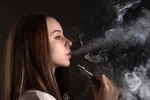 Free photo the face of vaping young woman at black studio