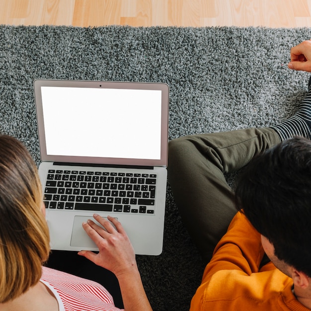 Faceless couple using laptop on floor