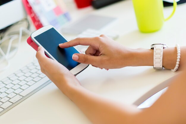 Faceless female using smartphone sitting by table