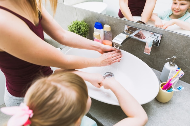 Faceless girl and woman washing hands