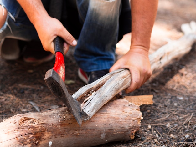 Faceless lumberman chopping log in forest