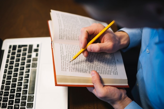 Faceless man making notes in book