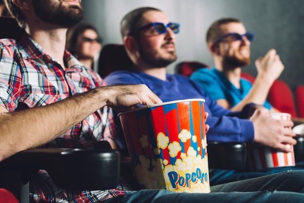 Faceless men watching film in cinema