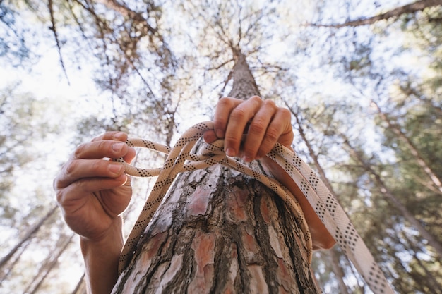 Free photo faceless person tying rope around tree