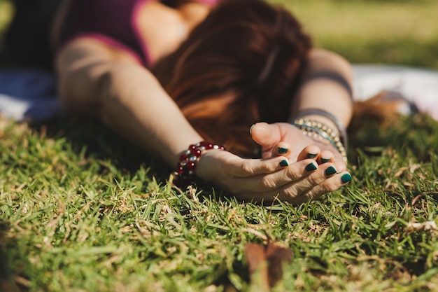 Faceless woman lying on grass