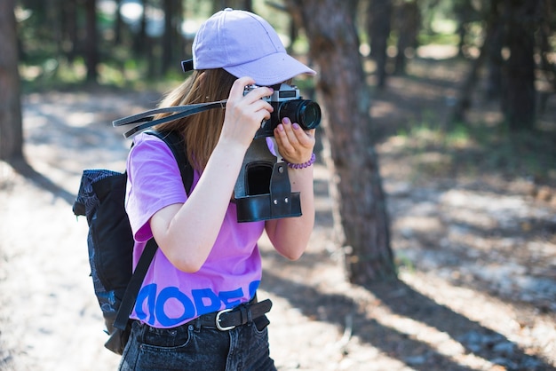 Faceless woman taking pictures in forest