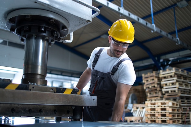 Factory employee working on industrial drilling machine at production line