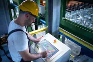 Free photo factory worker monitoring industrial machines and production remotely in control room