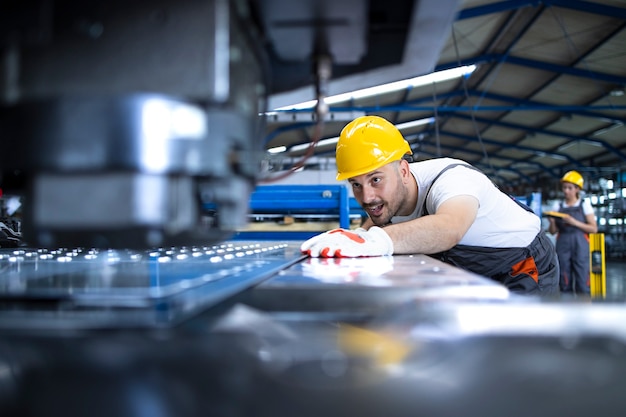 Free Photo factory worker in protective uniform and hardhat operating industrial machine at production line