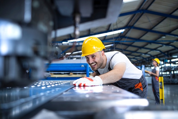 Free Photo factory worker in protective uniform and hardhat operating industrial machine at production line