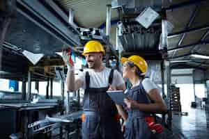 Free photo factory workers checking inventory with tablet computer in industrial warehouse full of metal parts