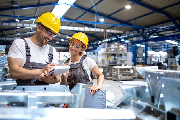 Factory workers checking quality of products in large industrial hall