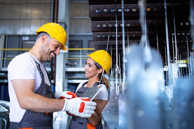 Free photo factory workers working together in industrial metal production line hall