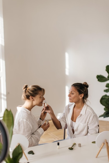 Free photo fair-skinned young blonde women are testing new facial serum while sitting at table indoors. cosmetic procedures concept