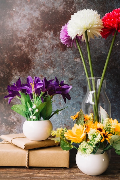 Free Photo fake flowers in different type of vase with wrapped gift boxes against grunge background