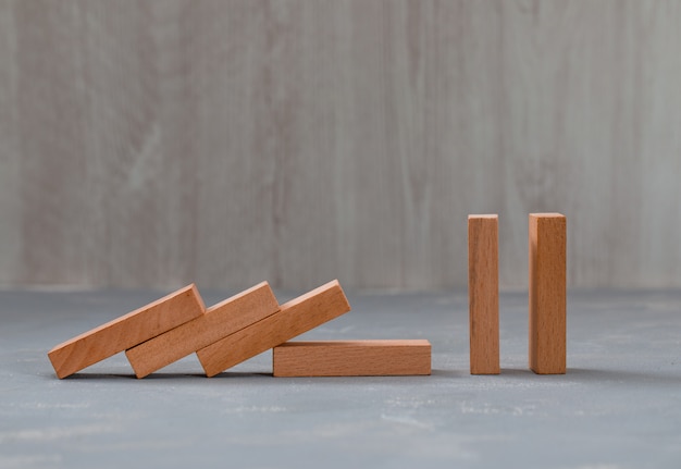 Free photo falling and standing wooden blocks on plaster and wooden table