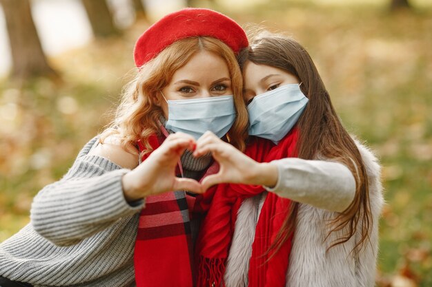 Family in a autumn park. Coronavirus theme. Mother with daughter.