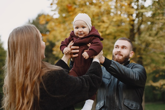 Free photo family in a autumn park. man in a black jacket. cute little girl with parents.