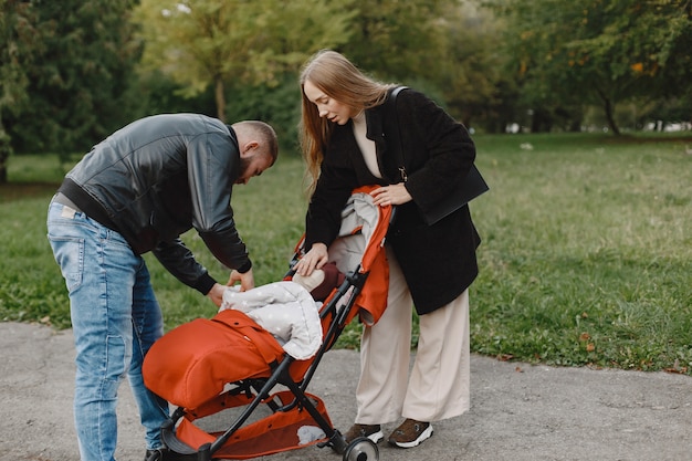 Family in a autumn park. Man in a black jacket. Cute little girl with parents.