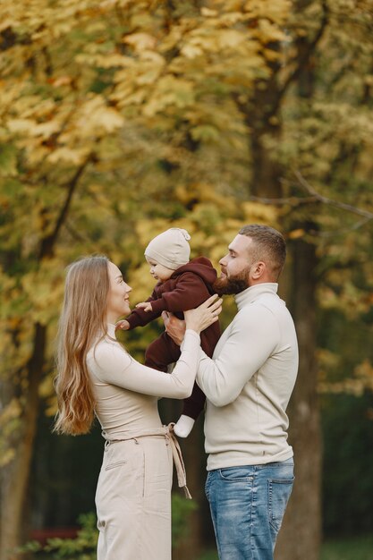 Family in a autumn park. Man in a brown sweater. Cute little girl with parents.