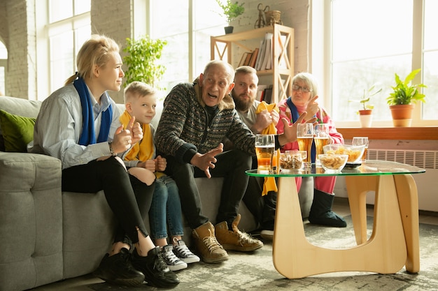 Free photo family cheering and watchin tv at home in the living room