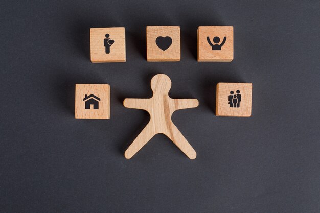 Family concept with icons on wooden cubes, human figure on dark grey table flat lay.