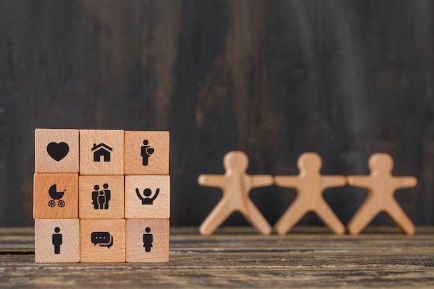 Free photo family concept with icons on wooden cubes, human figures on wooden table side view.