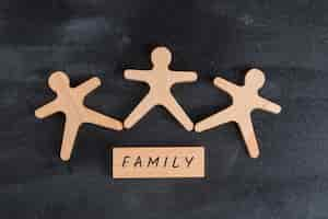 Free photo family concept with wooden block and human figures on dark grey table flat lay.