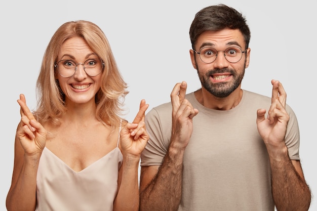 Family couple cross fingers, believe in good luck, pray for good wellness