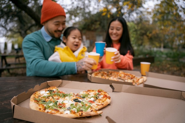 Free photo family eating pizza outdoors front view